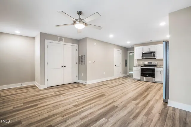 an empty room with wooden floor ceiling fan and windows
