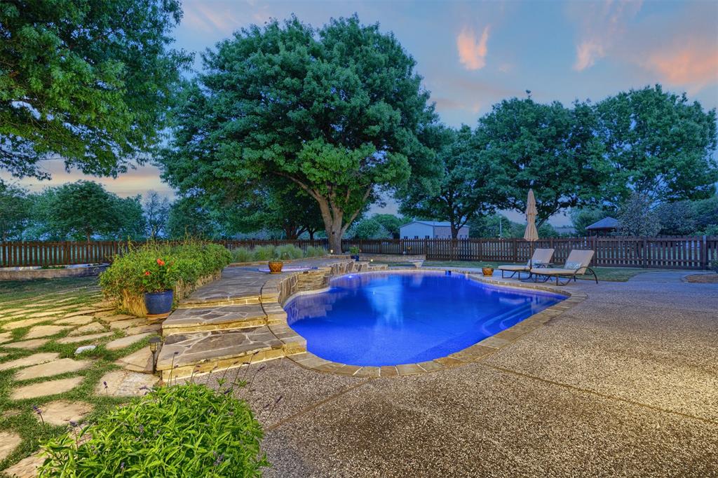 The property features a swimming pool with a stone surround and a concrete patio