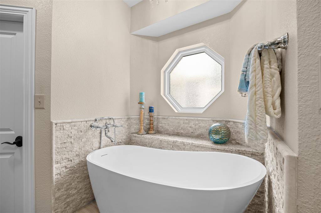 7225 Moss Ridge Road Parker, TX 75098 - Photo 11 of 40 The bathroom features a freestanding soaking tub with a wall-mounted faucet, an octagonal window, and tiled wainscoting