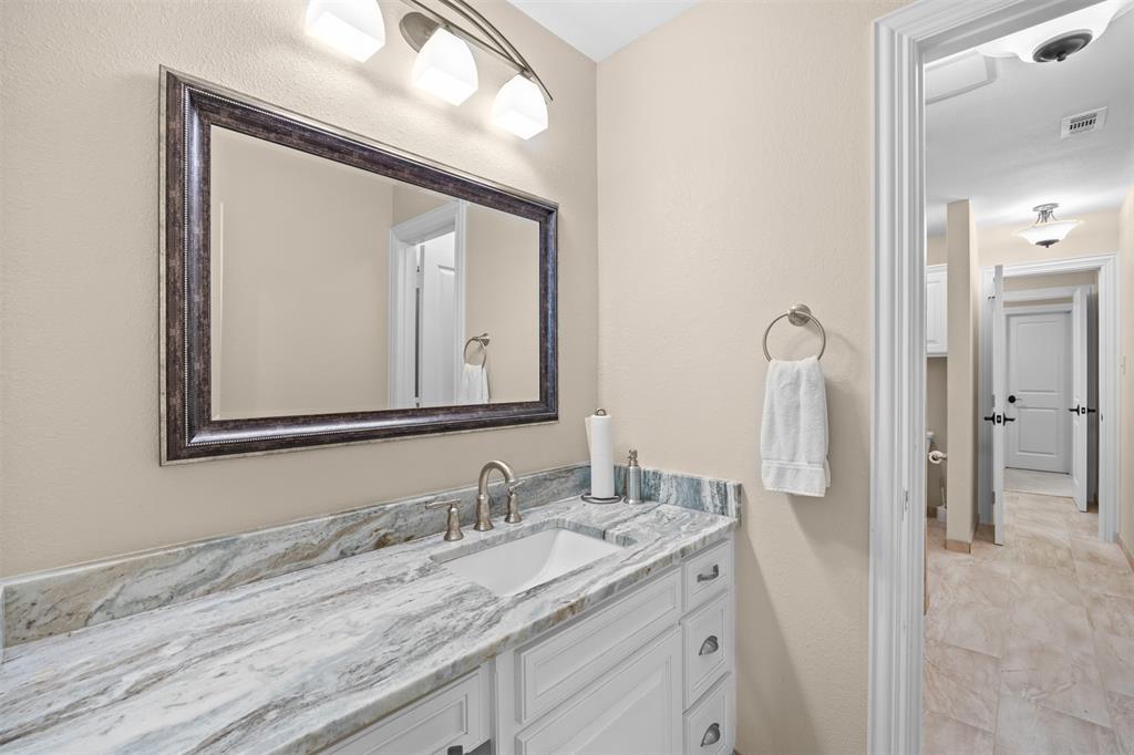 7225 Moss Ridge Road Parker, TX 75098 - Photo 14 of 40 The property features a bathroom with a vanity, a rectangular sink, a light-colored countertop, and a framed mirror
