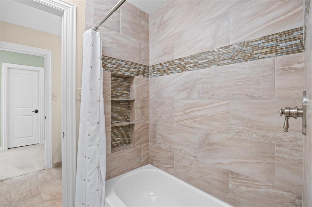 7225 Moss Ridge Road Parker, TX 75098 - Photo 15 of 40 Bathroom features a bathtub with tiled walls, brushed nickel fixtures, and a decorative mosaic tile accent band