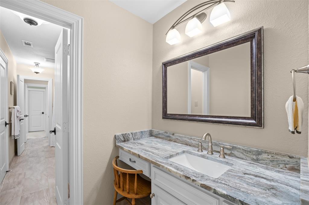 7225 Moss Ridge Road Parker, TX 75098 - Photo 16 of 40 This bathroom features a vanity with a light-colored countertop and an integrated sink, complemented by a large framed mirror and an overhead light fixture