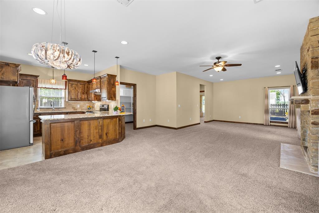 7225 Moss Ridge Road Parker, TX 75098 - Photo 22 of 40 Spacious living area featuring light-colored carpet flooring, a stone fireplace, and a ceiling fan