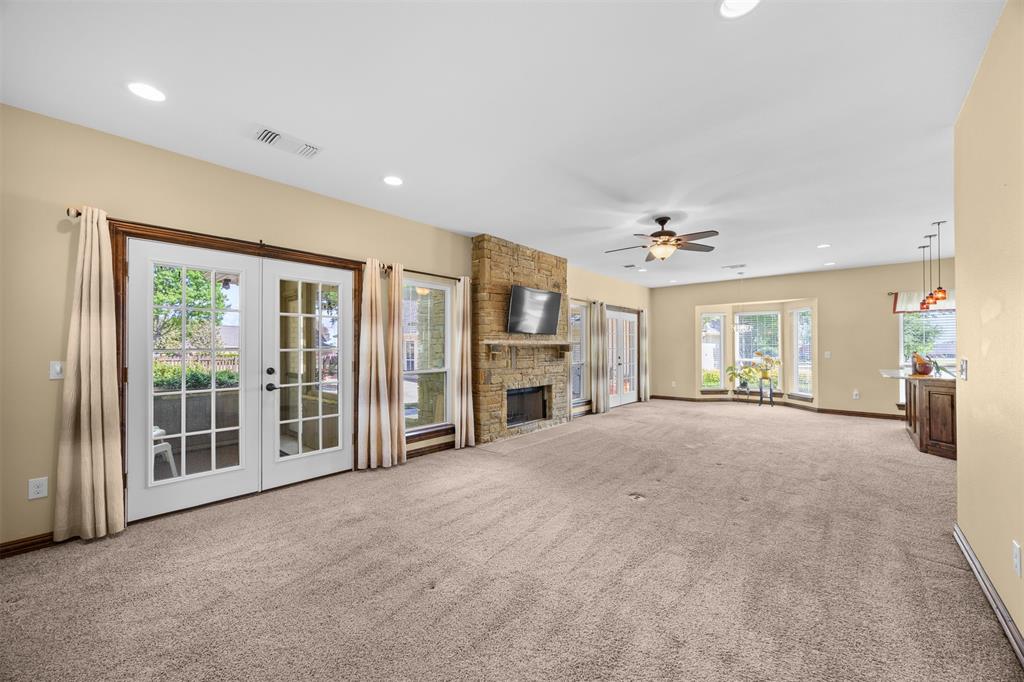 7225 Moss Ridge Road Parker, TX 75098 - Photo 23 of 40 Expansive living area featuring carpeted floors, a stone fireplace, recessed lighting, and french doors
