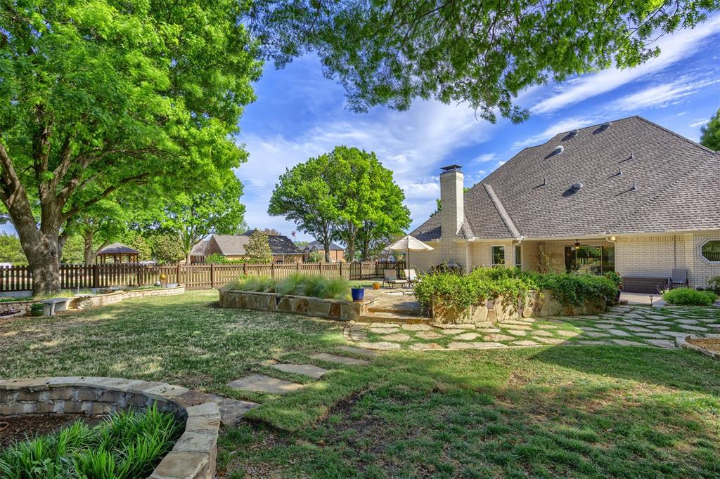 7225 Moss Ridge Road Parker, TX 75098 - Photo 32 of 40 Expansive backyard with a well-maintained lawn, mature trees, and a stone patio area