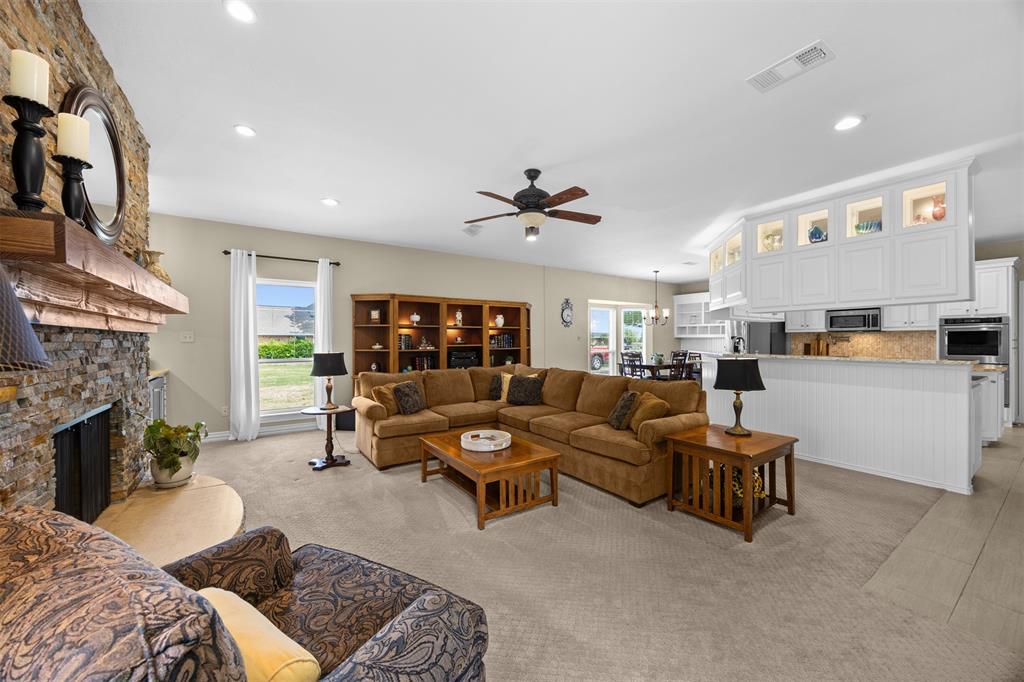 7225 Moss Ridge Road Parker, TX 75098 - Photo 8 of 40 This spacious living area features a stone fireplace with a wooden mantel, built-in wooden shelving, and a ceiling fan