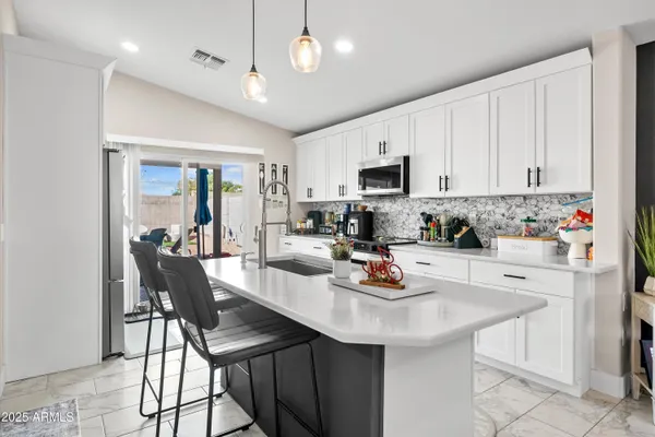 a kitchen with stainless steel appliances kitchen island granite countertop a table chairs in it and white cabinets