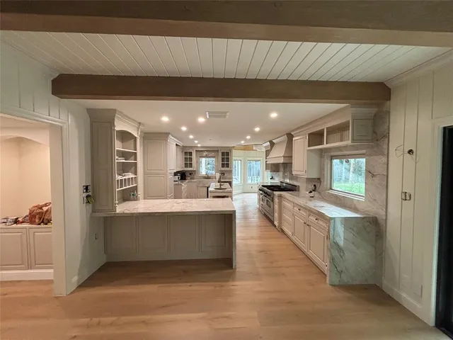 a large white kitchen with kitchen island a sink a stove and a refrigerator