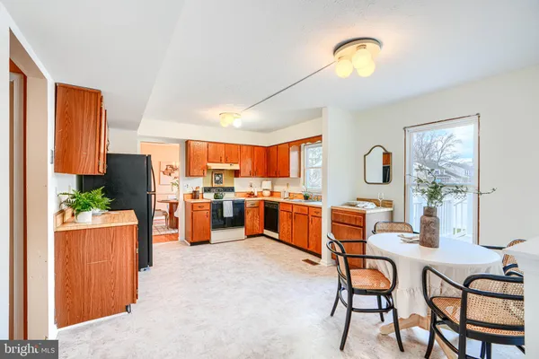 a kitchen with stainless steel appliances kitchen island granite countertop dining table chairs and a large window
