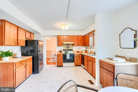 a open kitchen with stainless steel appliances granite countertop a refrigerator a sink dishwasher stove top oven a dining table and chairs with wooden floor