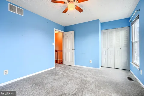 an empty room with closet and a chandelier fan