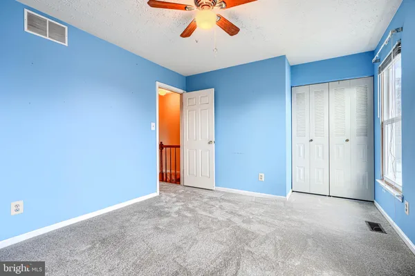 an empty room with closet and a chandelier fan