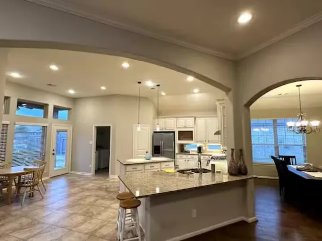 a kitchen with stainless steel appliances granite countertop a sink refrigerator and chairs