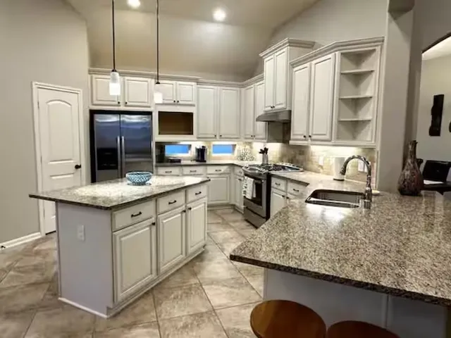 a kitchen with stainless steel appliances granite countertop a sink a stove counter space and cabinets
