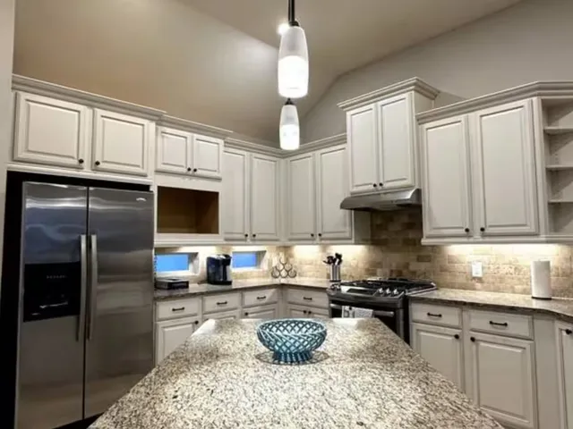 a kitchen with granite countertop kitchen island stainless steel appliances a stove a refrigerator a sink a window and cabinets