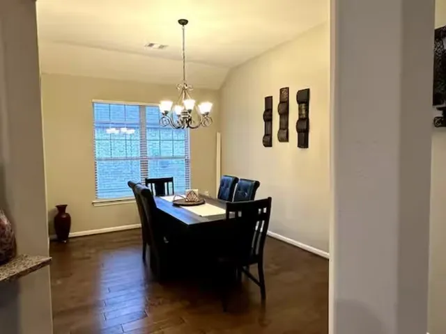a dining room with furniture a chandelier and wooden floor