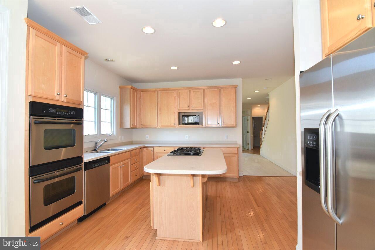 4619 Beaufont Spring Court Woodbridge, VA 22192 - Photo 13 of 42 a kitchen with stainless steel appliances granite countertop a refrigerator a stove top oven a sink dishwasher and wooden floor