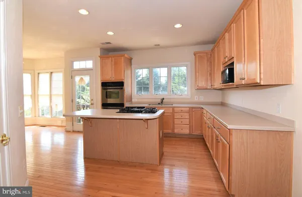 a kitchen with stainless steel appliances granite countertop a stove a sink dishwasher and a microwave oven with wooden floor