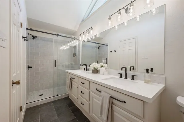 a bathroom with a shower sink vanity granite and mirror