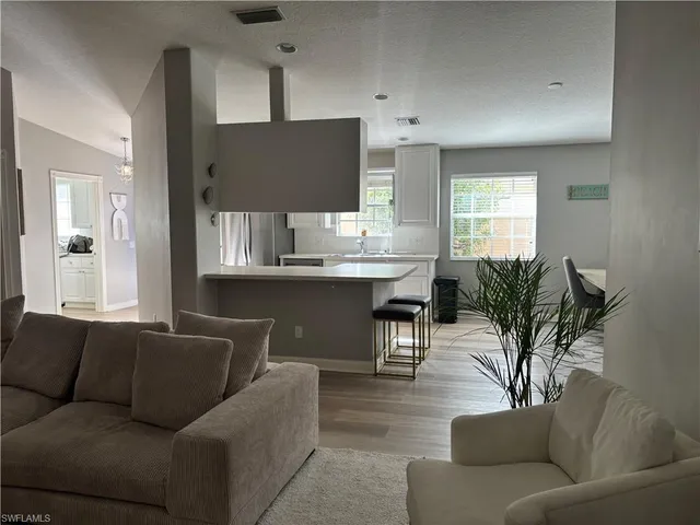 a living room with furniture kitchen view and a potted plant