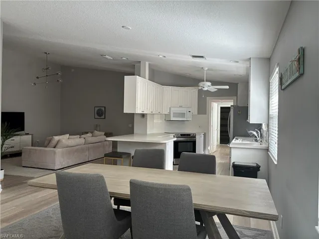 a living room with stainless steel appliances furniture a rug and a view of kitchen