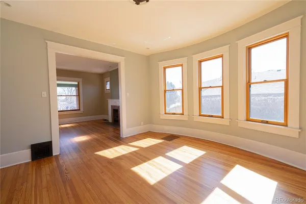 an empty room with wooden floor and windows