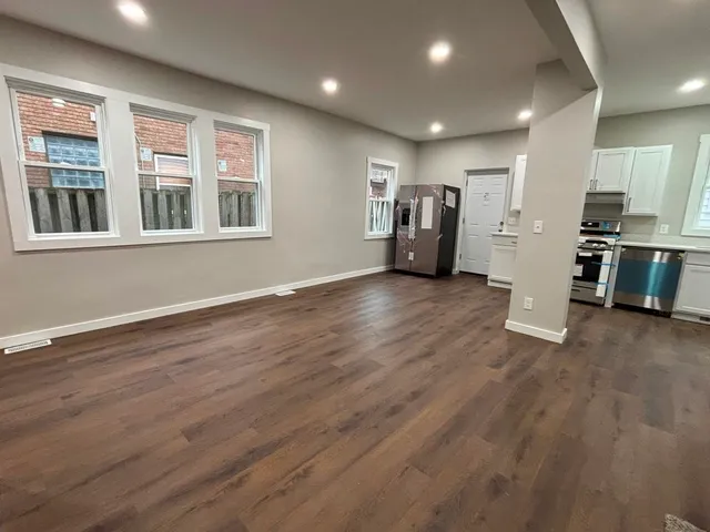 a view of a big room with wooden floors kitchen view and windows