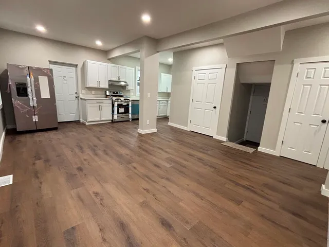 a view of a electric appliances in kitchen and empty room with wooden floor
