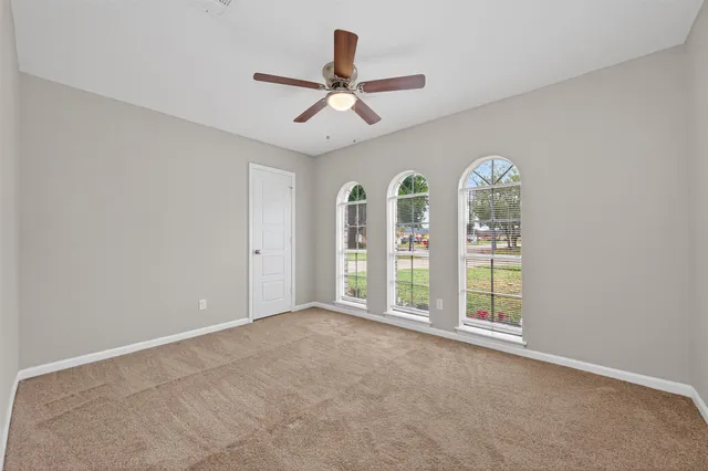an empty room with windows and ceiling fan
