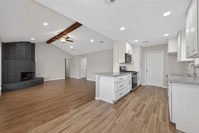 a large kitchen with stainless steel appliances granite countertop a large center island attached withe living room