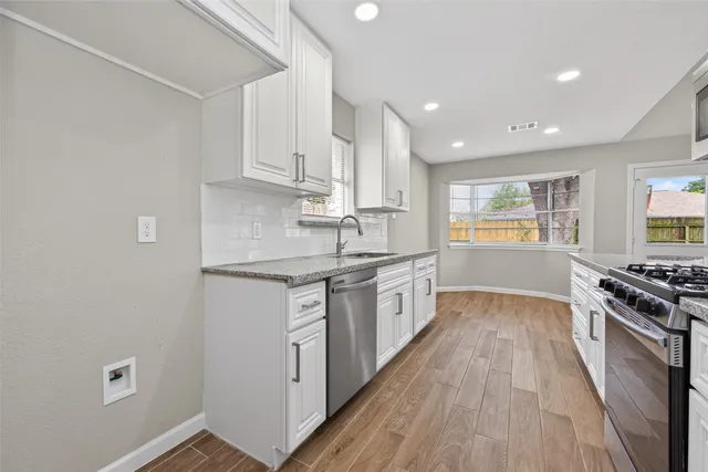 a kitchen with granite countertop a sink stove and cabinets