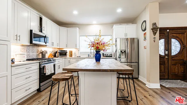 a kitchen with stainless steel appliances a sink a refrigerator a stove and a window