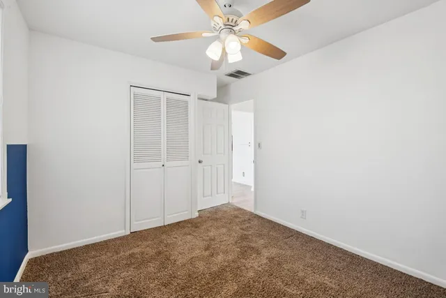 an empty room with a chandelier fan and closet