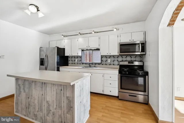 a kitchen with kitchen island white cabinets and stainless steel appliances