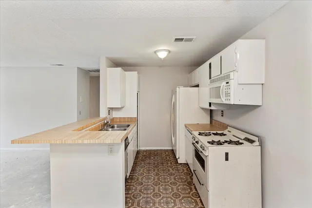 a kitchen that has a cabinets a stove a sink and a refrigerator with wooden floor