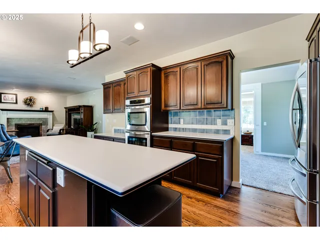 a kitchen with stainless steel appliances granite countertop a sink a stove and a wooden cabinets