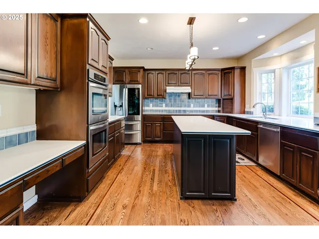 a kitchen with stainless steel appliances granite countertop a stove a refrigerator a kitchen island a table and chairs