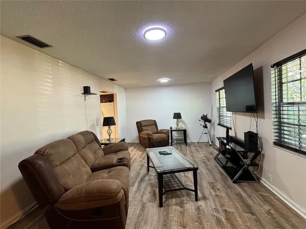 a living room with furniture a flat screen tv and kitchen view