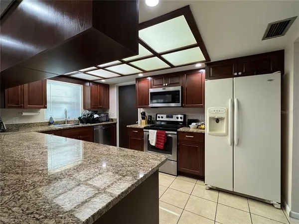 a kitchen with stainless steel appliances granite countertop a refrigerator a stove and a sink