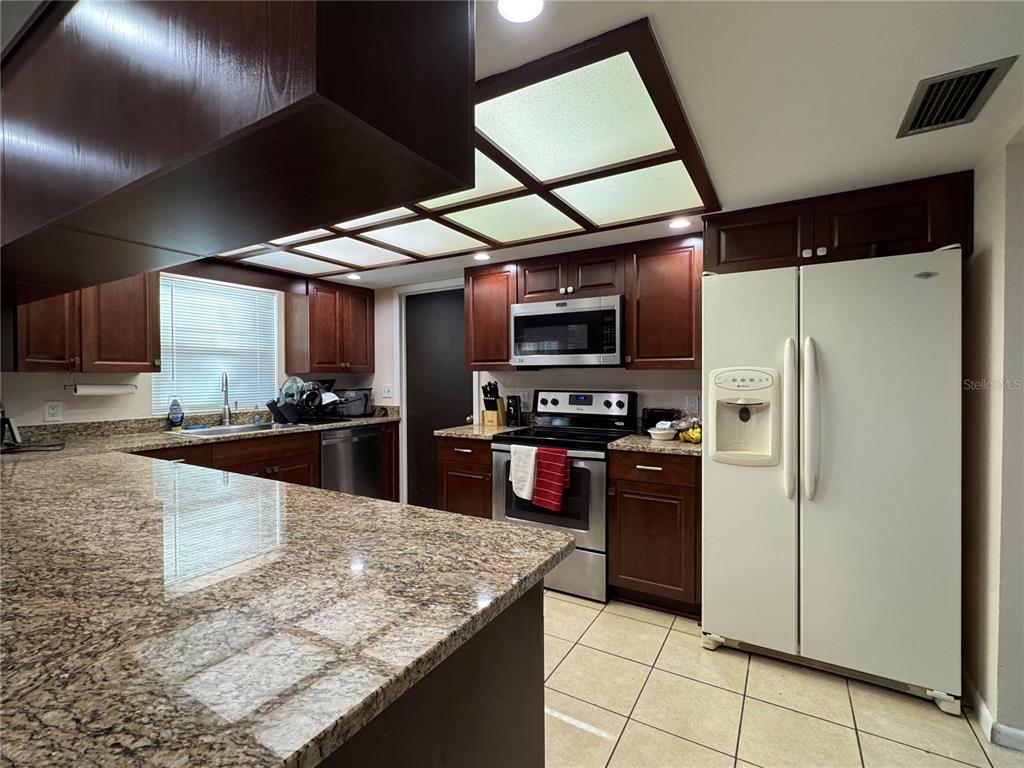 1703 North Taylor Road Brandon, FL 33510 - Photo 17 of 32 a kitchen with stainless steel appliances granite countertop a refrigerator a stove and a sink