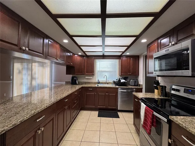 a large kitchen with stainless steel appliances granite countertop a stove sink and cabinets