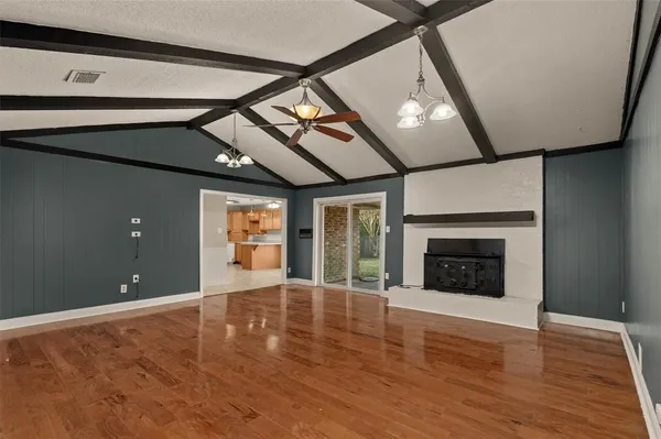 a view of an empty room with wooden floor fireplace and a window