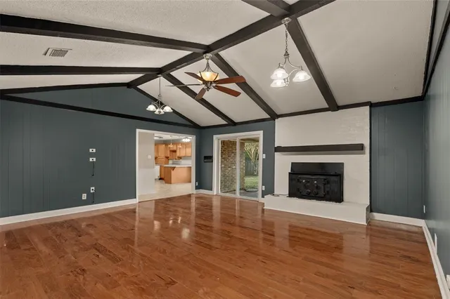 a view of an empty room with wooden floor fireplace and a window