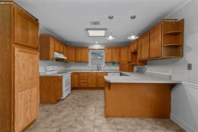 a kitchen with stainless steel appliances granite countertop a stove a sink dishwasher and a refrigerator with wooden cabinets