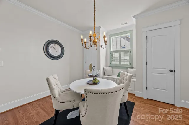 a dining room with chandelier and wooden floor