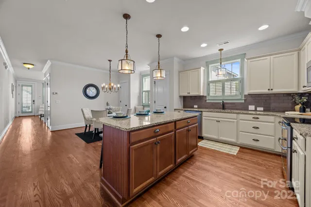 a large kitchen with kitchen island a stove a sink a center island and wooden floor