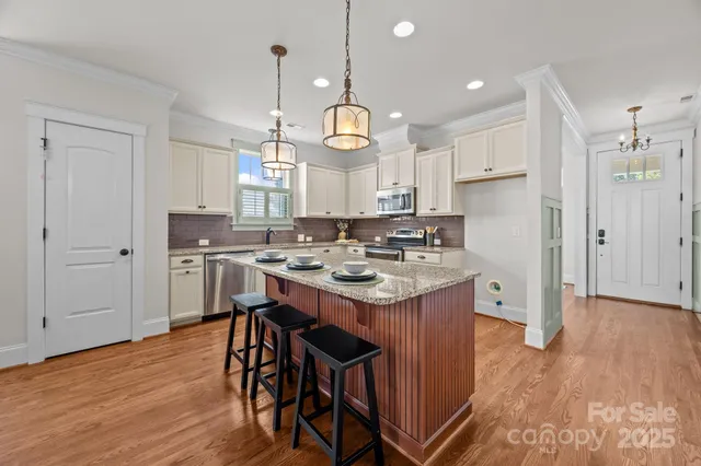 a kitchen with granite countertop a stove a sink dishwasher a refrigerator and a dining table with wooden floor