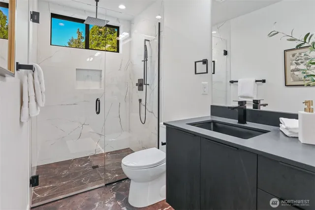 a bathroom with a granite countertop sink a mirror a toilet and shower