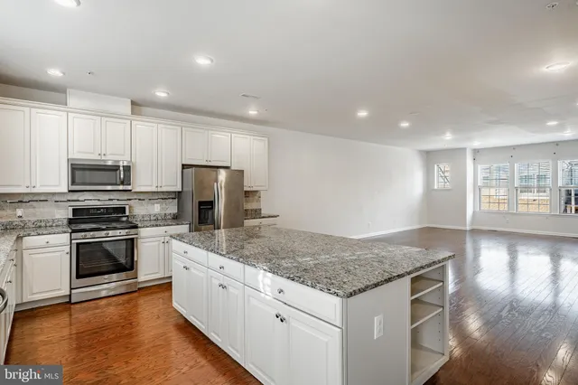 a kitchen with stainless steel appliances granite countertop a refrigerator and a stove top oven