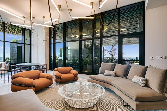 a living room with furniture a chandelier and a floor to ceiling window